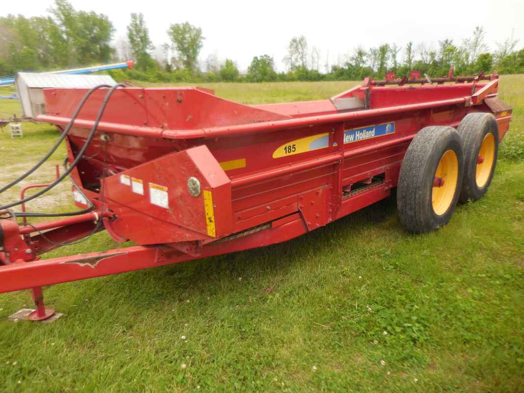 New Holland model 185 tandem axle manure spreader with end gate and top beater.