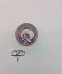 Studio glass paperweight with internal swirl and gold flecks on a purple base